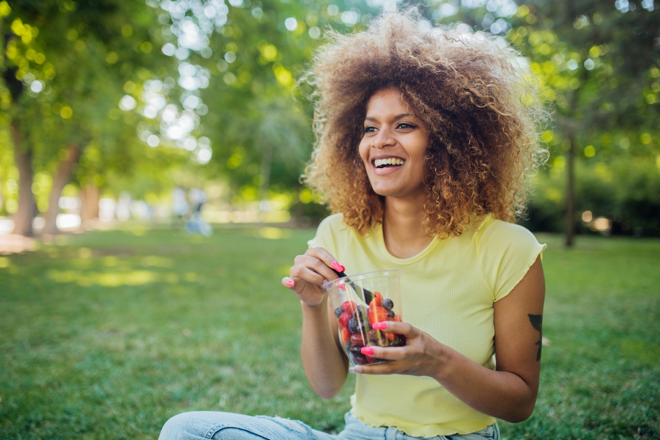 VegNews.SmilingEatingHealthySnacks.Getty