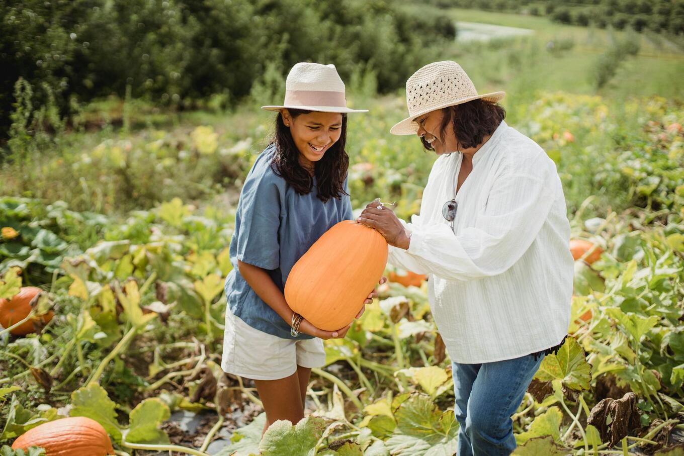 woman and girl with pumpkin in pumpkin patch
