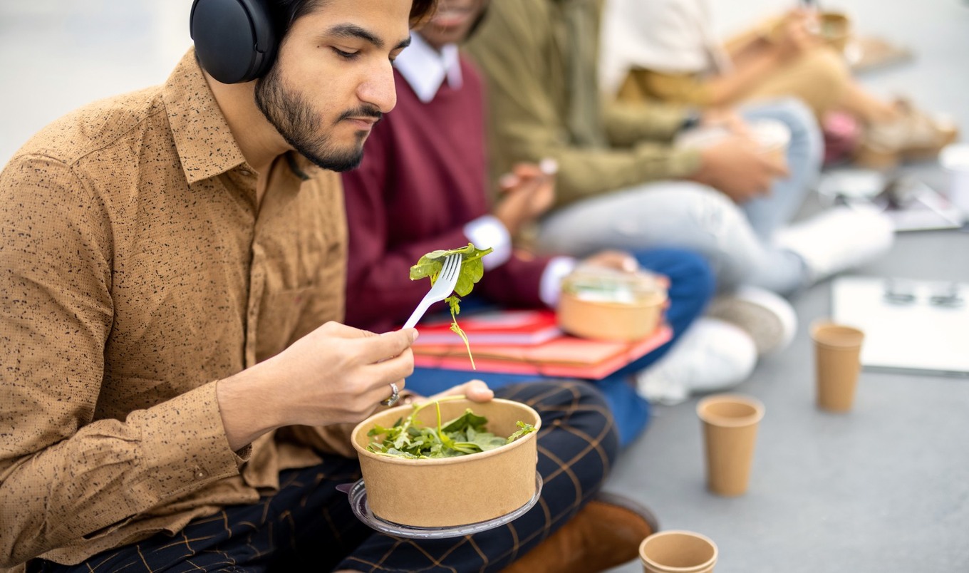 college student wearing headphones eating