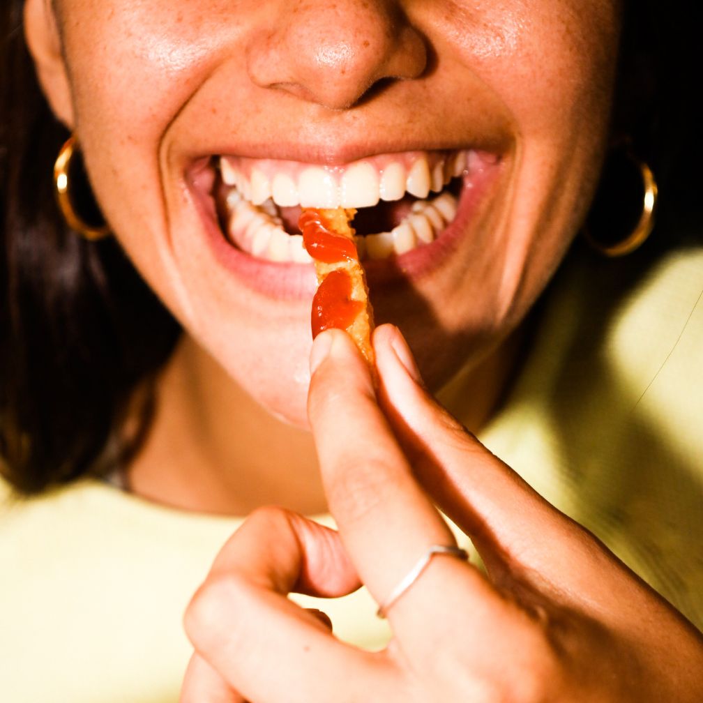 woman eating French fries with ketchup