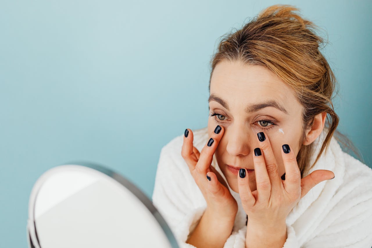 woman applies cream to eyes