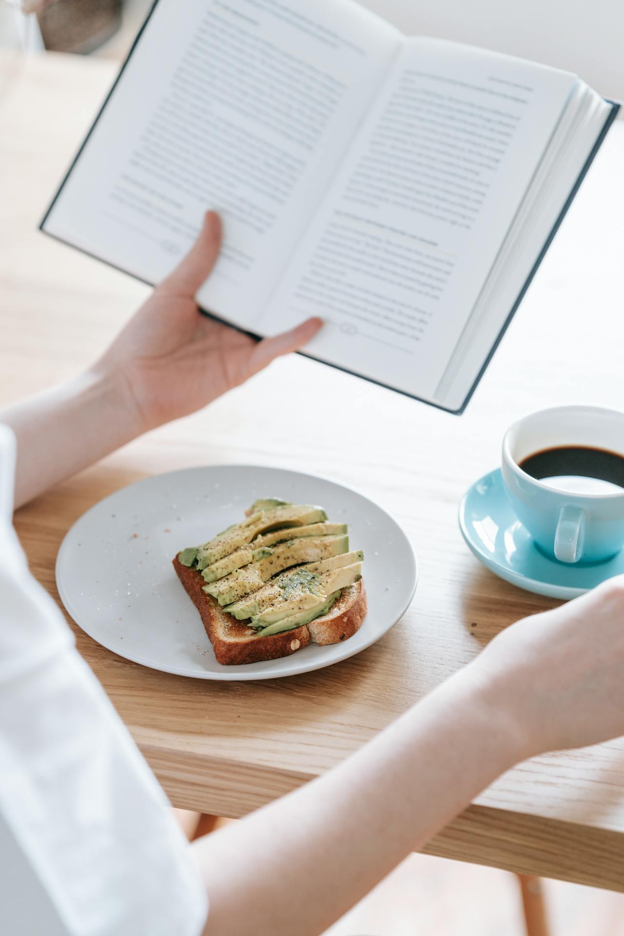 person reads book with avo toast